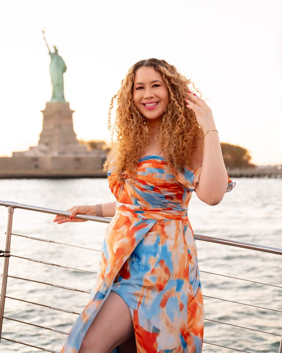 LeAura Luciano smiling on a boat in New York Harbor with the Statue of Liberty behind her